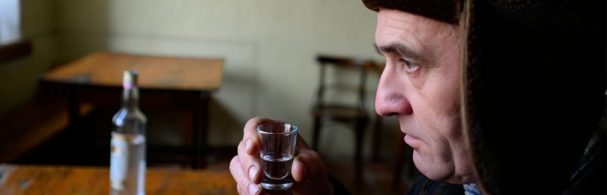 Мужчина пьет алкоголь из рюмки
